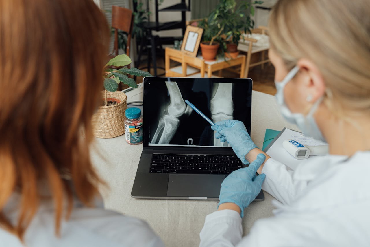 Two healthcare workers in a consultation reviewing x-ray images on a laptop.